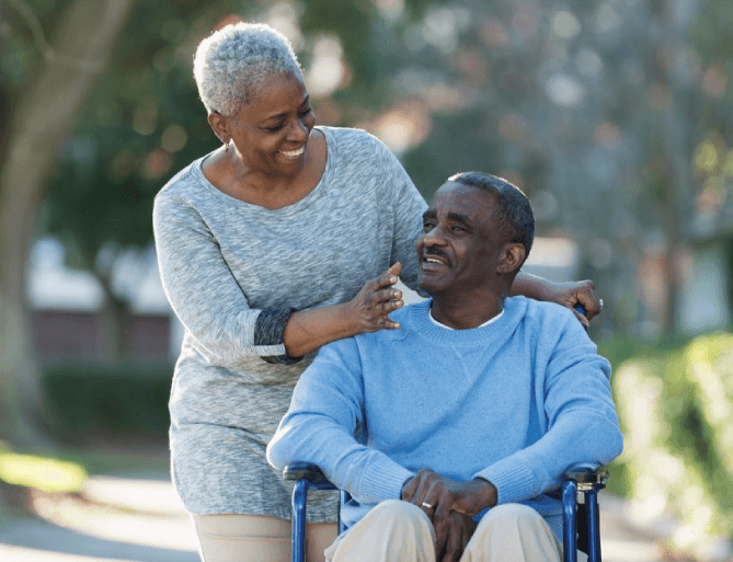 wife pushing her husband in his wheelchair