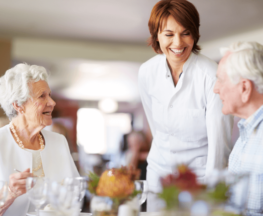 employee serving a senior couple dinner